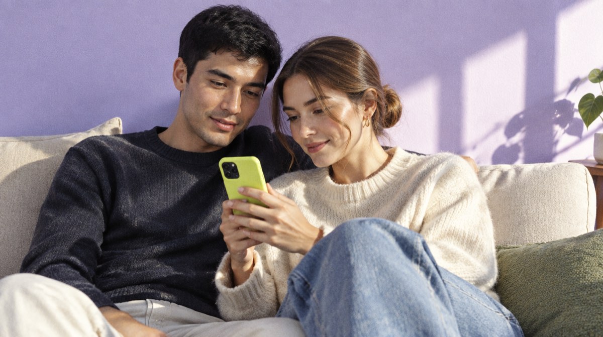 Una coppia sul divano legge sul telefono le condizioni del mutuo, fondiario o ipotecario
