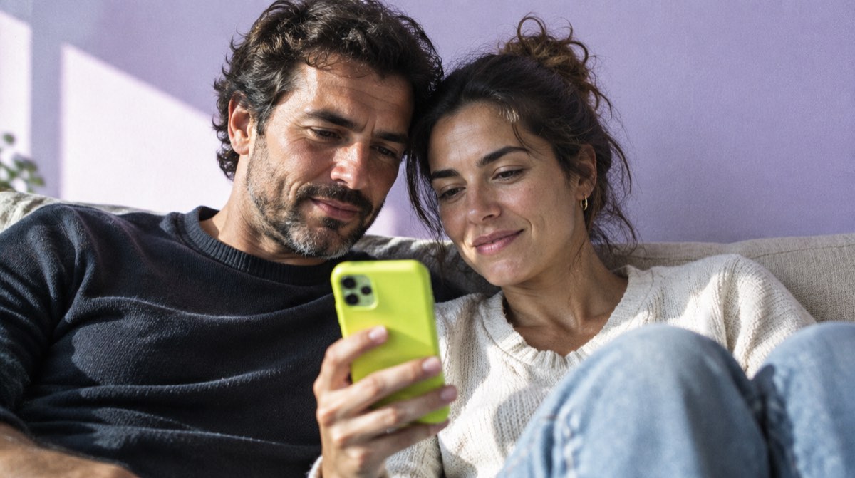 Due mani — una adulta e una più giovane — che sorreggono insieme un modellino di casa, con contratto e chiavi sullo sfondo — illustrazione editoriale su mutuo in comproprietà con genitori 2026
